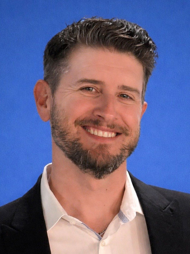 Headshot of Jeff Boron, Chief Digital Officer, of Touchdown Strategies. Image is of Jeff smiling wearing a white shirt and black jacket, all on a blue background.